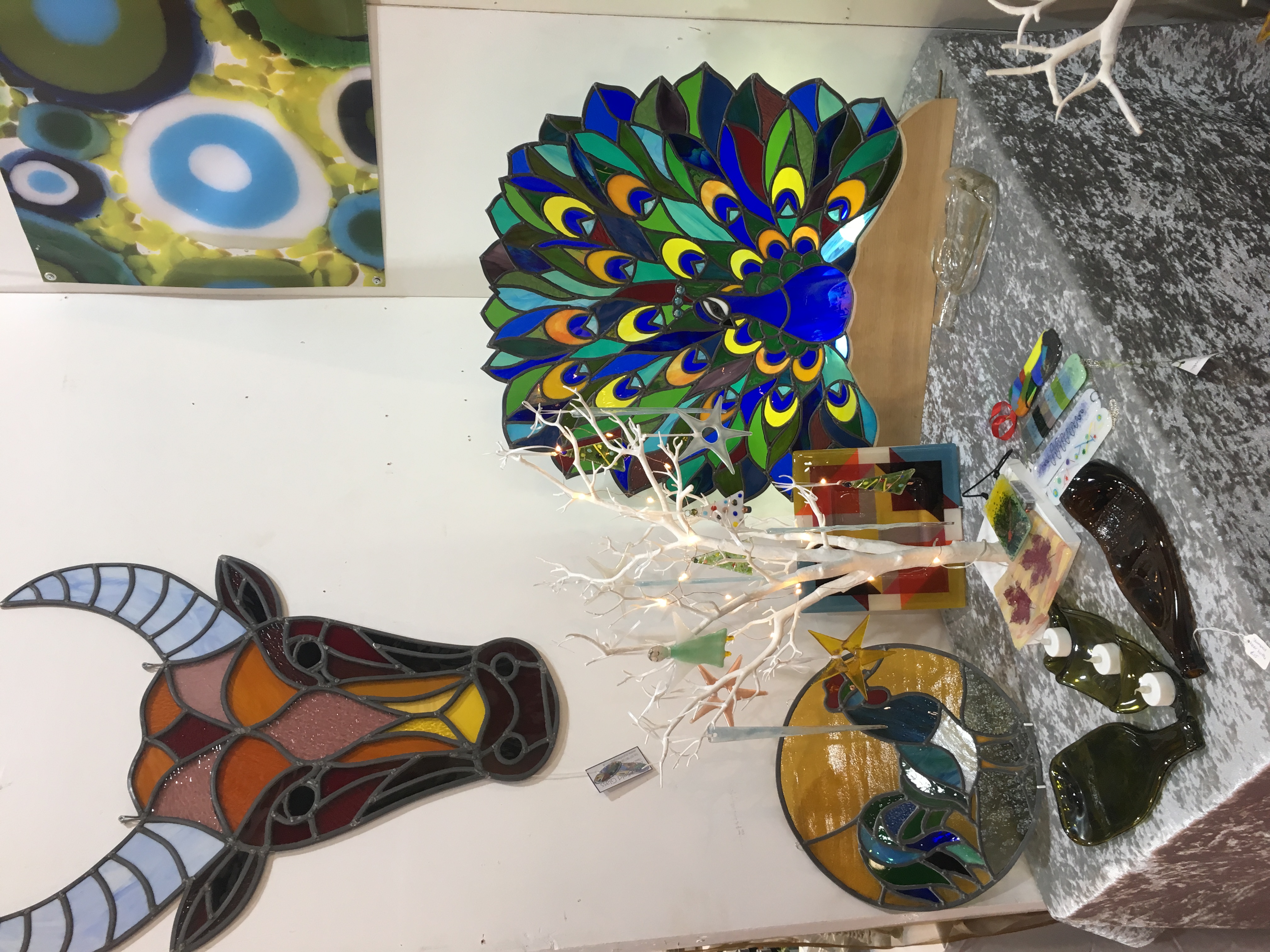 A display of larger free-standing stained glass works - a bull, peacock and cockerel